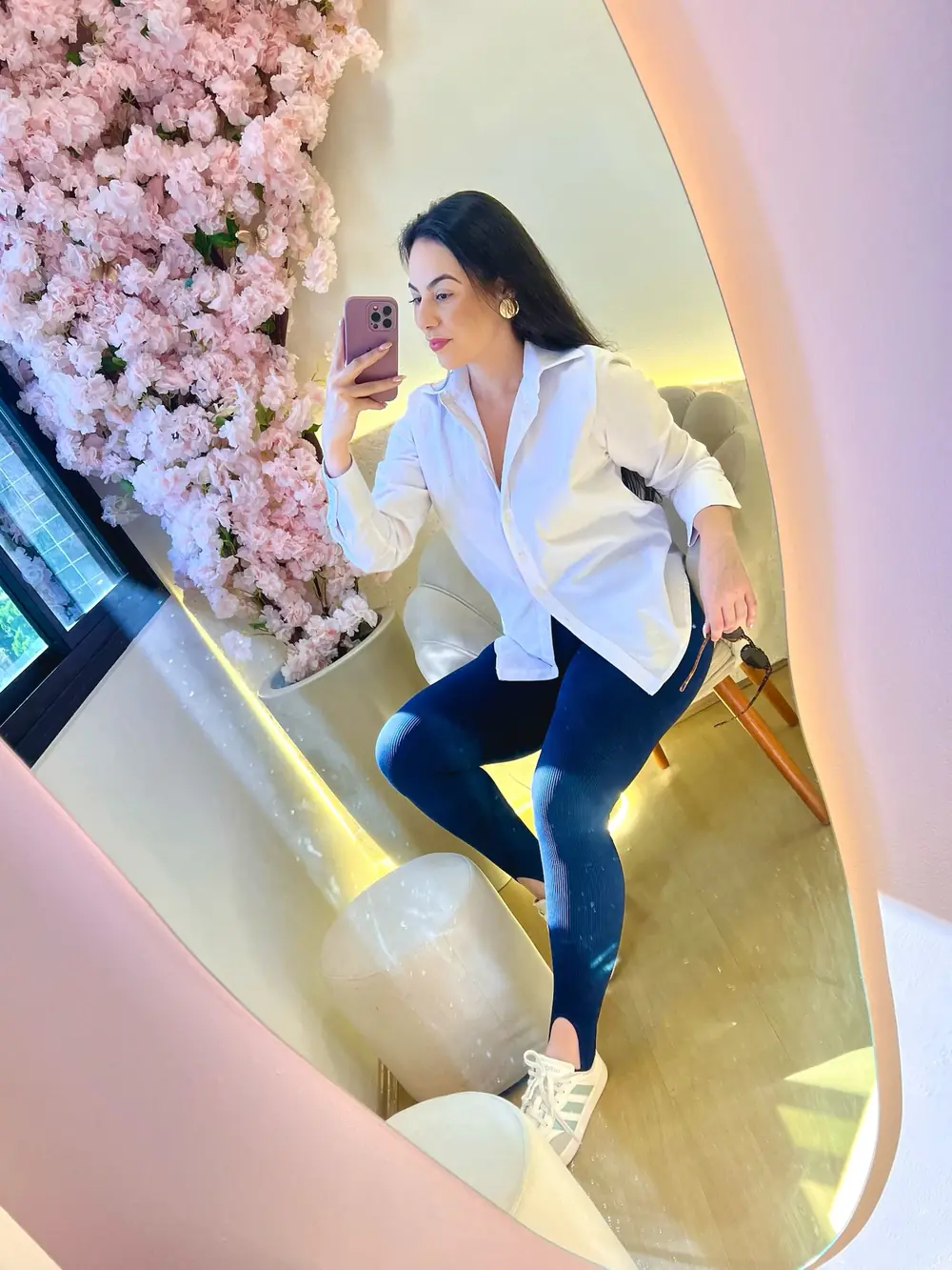 Modelo de camisa branca oversized e jeans diante de um espelho